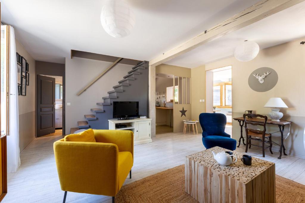 ein Wohnzimmer mit einem gelben Sofa und blauen Stühlen in der Unterkunft Mon Cottin dans le Vexin 