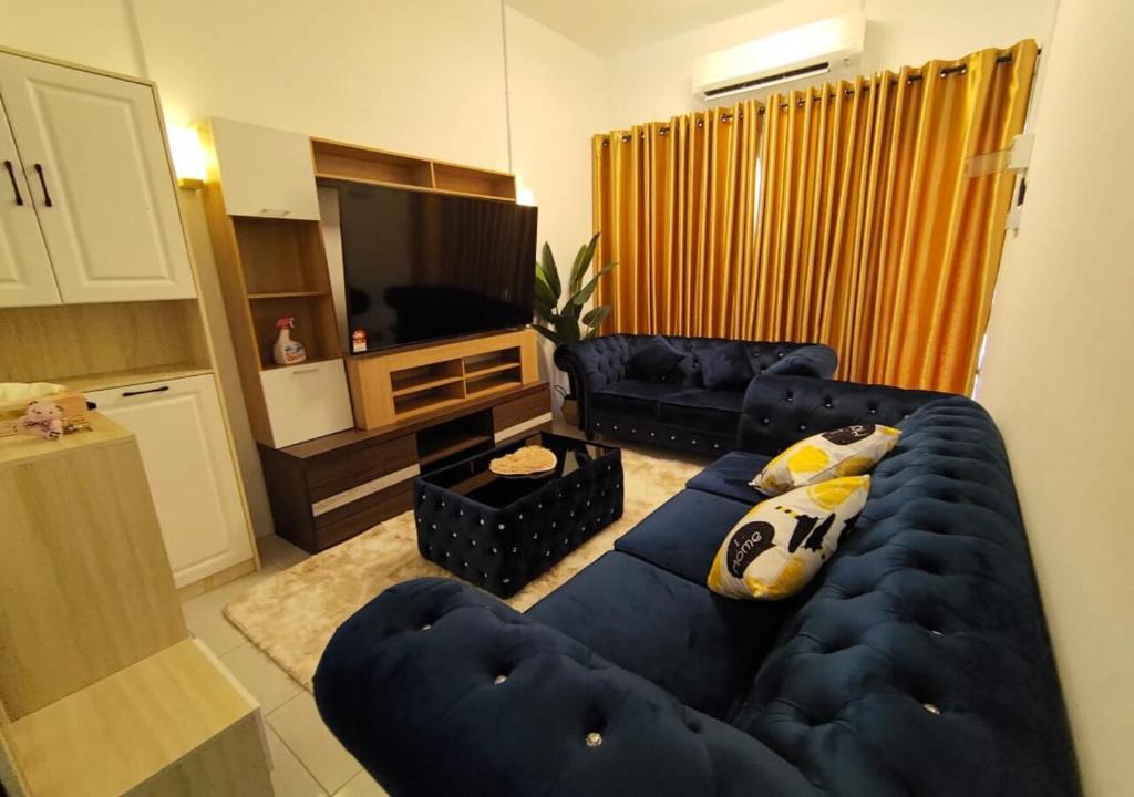 a living room with a blue couch and a television at HOMESTAY SYAABAN Kamunting Taiping Batu Kurau Ulu Sepetang in Kamunting