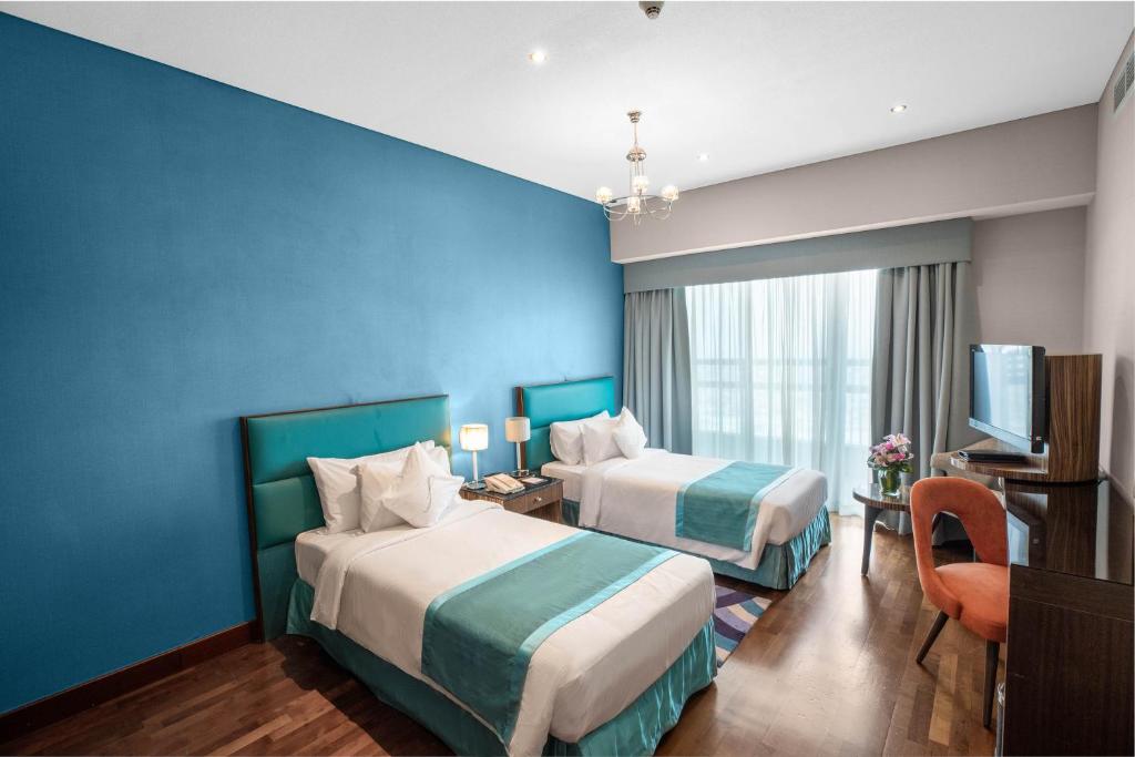 a hotel room with two beds and a blue wall at City Premiere Hotel Apartments - Dubai in Dubai
