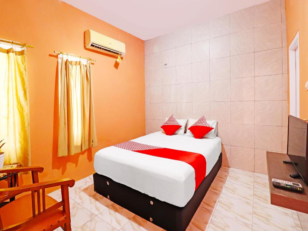 a bedroom with a bed with red and white pillows at OYO 91408 Kas Residence Syariah in Jambi