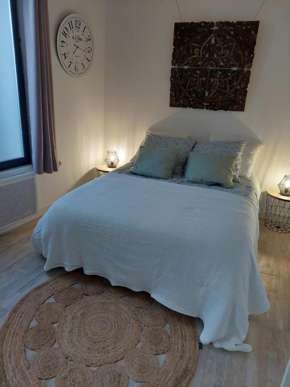 a bedroom with a large bed with a clock on the wall at Charmant Studio au calme 