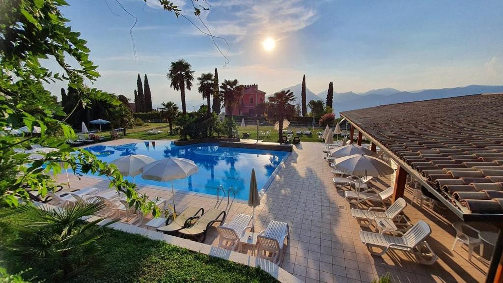 a pool with chairs and umbrellas next to a building at Hotel Diana in San Zeno di Montagna