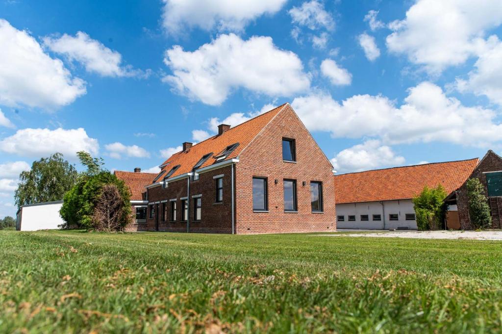 un edificio di mattoni con un prato di fronte di Farmhouse Hoeve Den Ast 5 separate bedrooms with bathrooms a Harelbeke