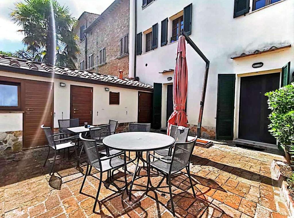 eine Terrasse mit einem Tisch, Stühlen und einem Sonnenschirm in der Unterkunft La Dormeuse in Lucignano