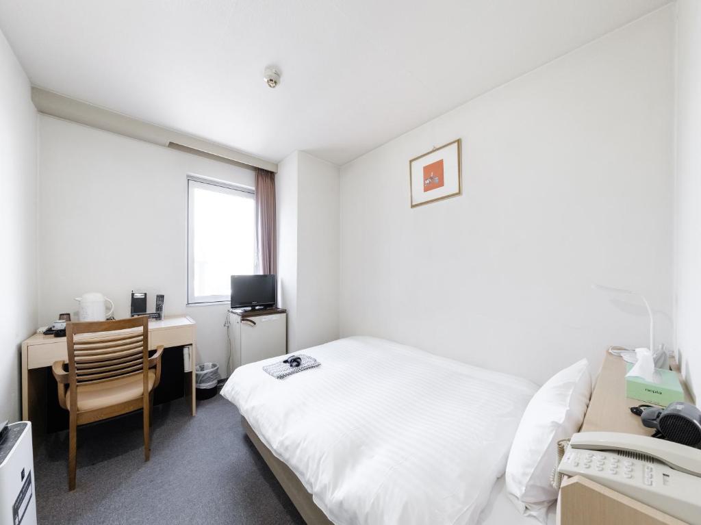 um quarto com uma cama, uma secretária e uma janela em Tabist THE GREEN ASAHIKAWA em Asahikawa