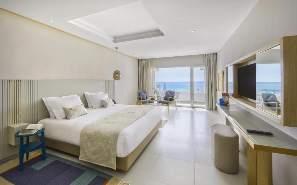 a hotel room with a bed and a view of the ocean at Royal Azur Thalassa in Hammamet