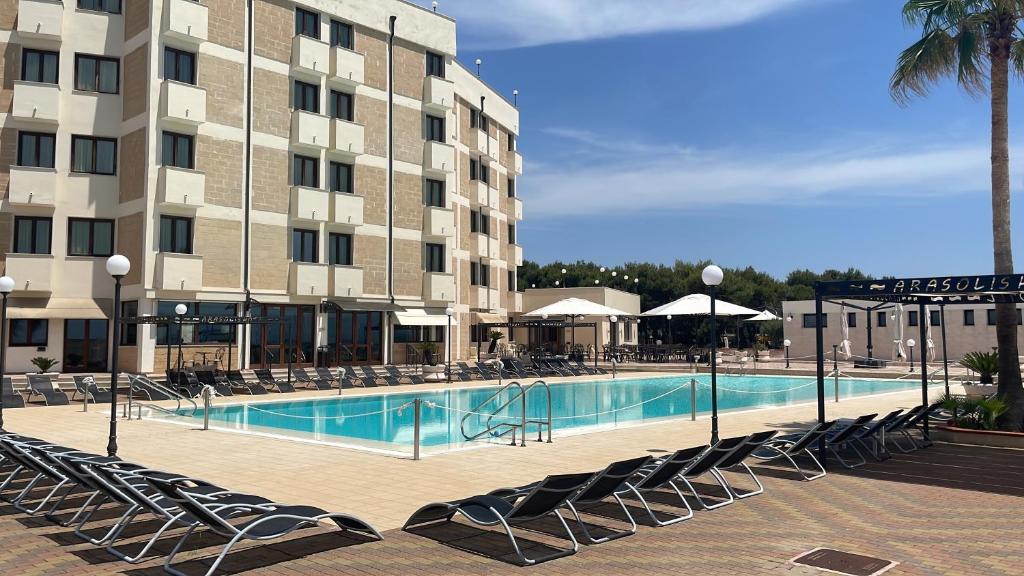 uma piscina de hotel com cadeiras e um edifício em Hotel Ara Solis em Lido Azzurro