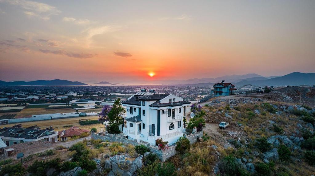 una casa en una colina con la puesta de sol en el fondo en Sessiz,Sakin, huzurlu jakuzi ve saunalı deniz,doğa manzaralı müstakil villa en Fethiye