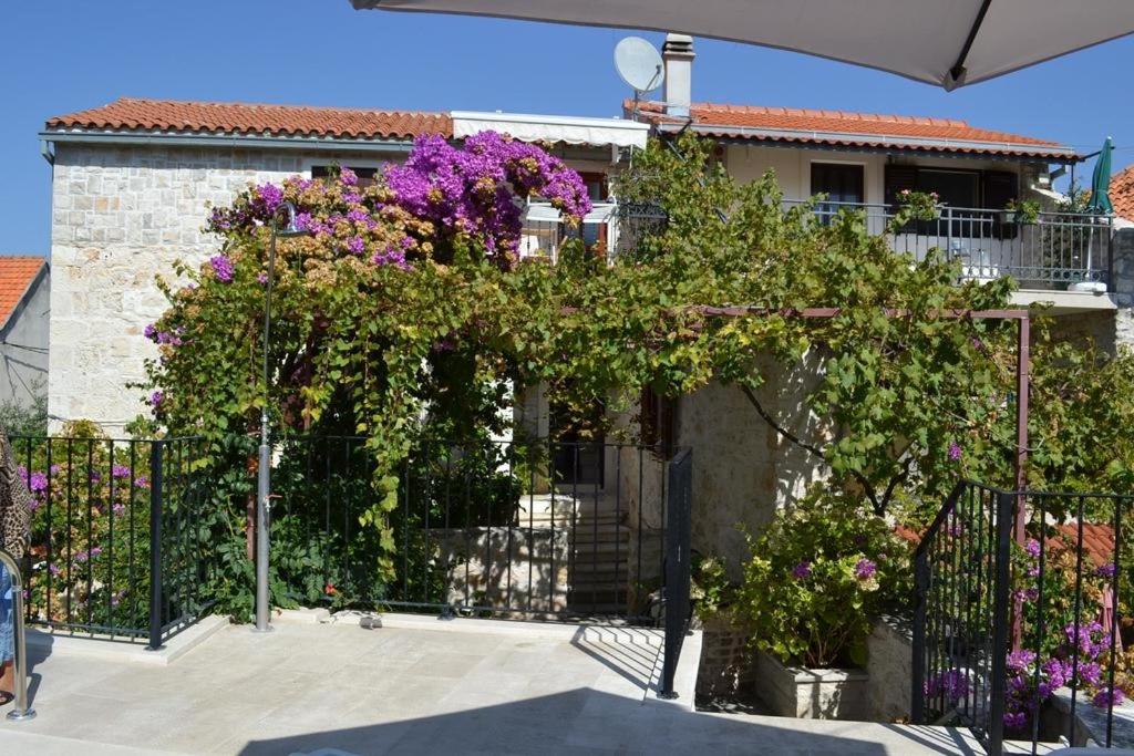 a building with a fence with purple flowers on it at Family friendly apartments with a swimming pool Sutivan, Brac - 14737 in Sutivan