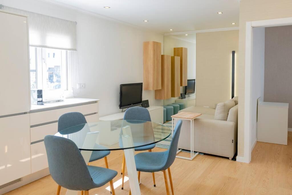 a dining room with a glass table and blue chairs at The Modern 1385 Apartment in Batalha