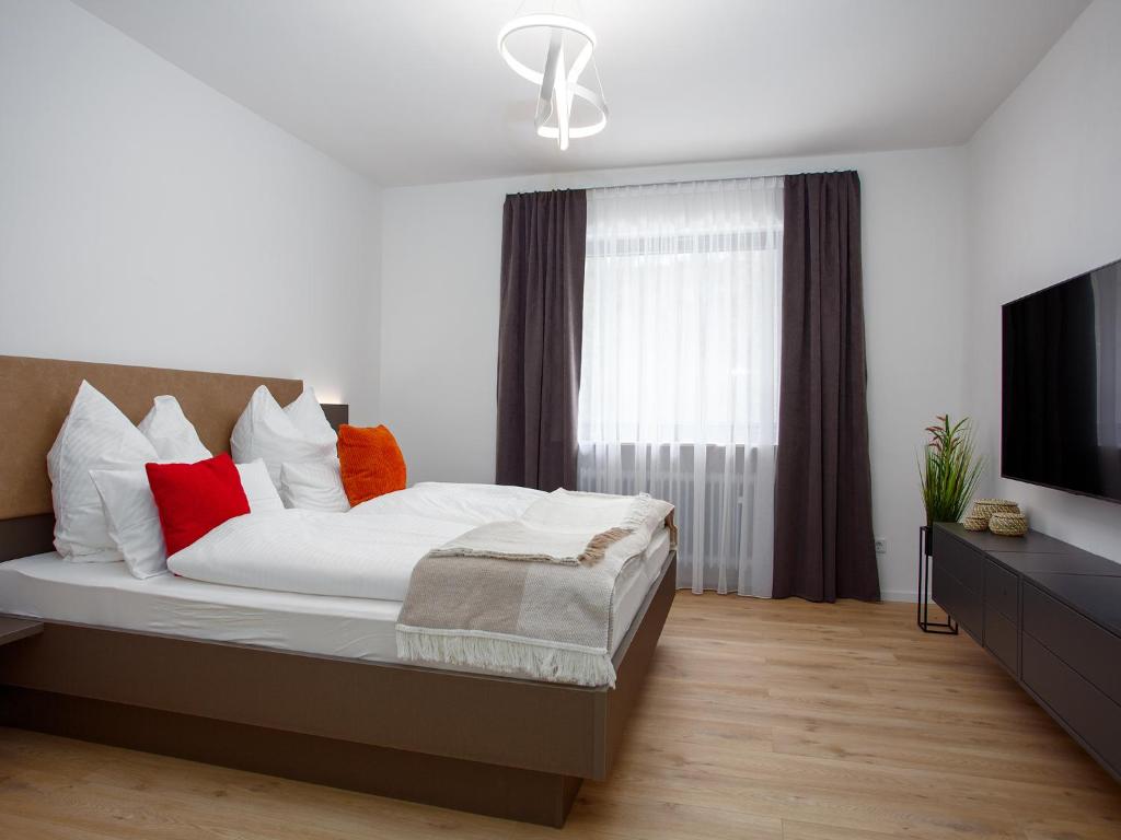 a bedroom with a bed with red pillows and a television at Zwick Apartments in Kammerstein