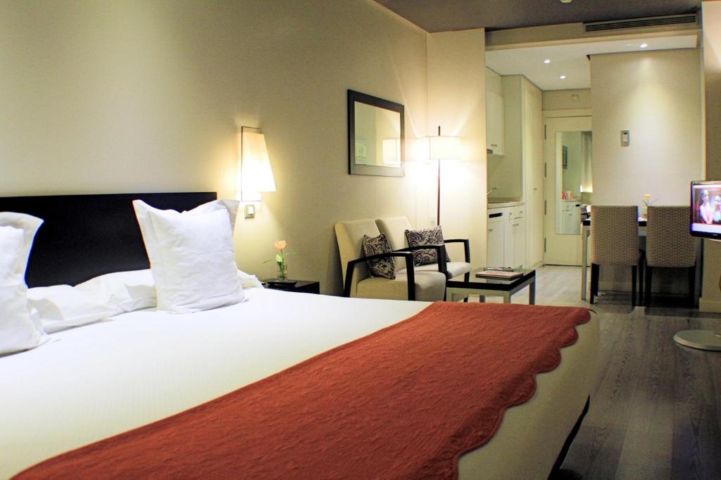 マドリードにあるスイーツ ウィーン プラザ デ エスパーニャの大きなベッドとリビングルームが備わるホテルルームです。