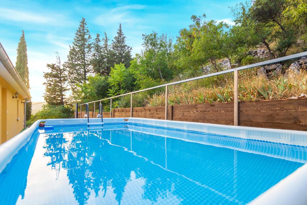 a blue swimming pool with a fence and trees at HOLIDAY HOME IVA, Proložac - Makarska in Donji Proložac