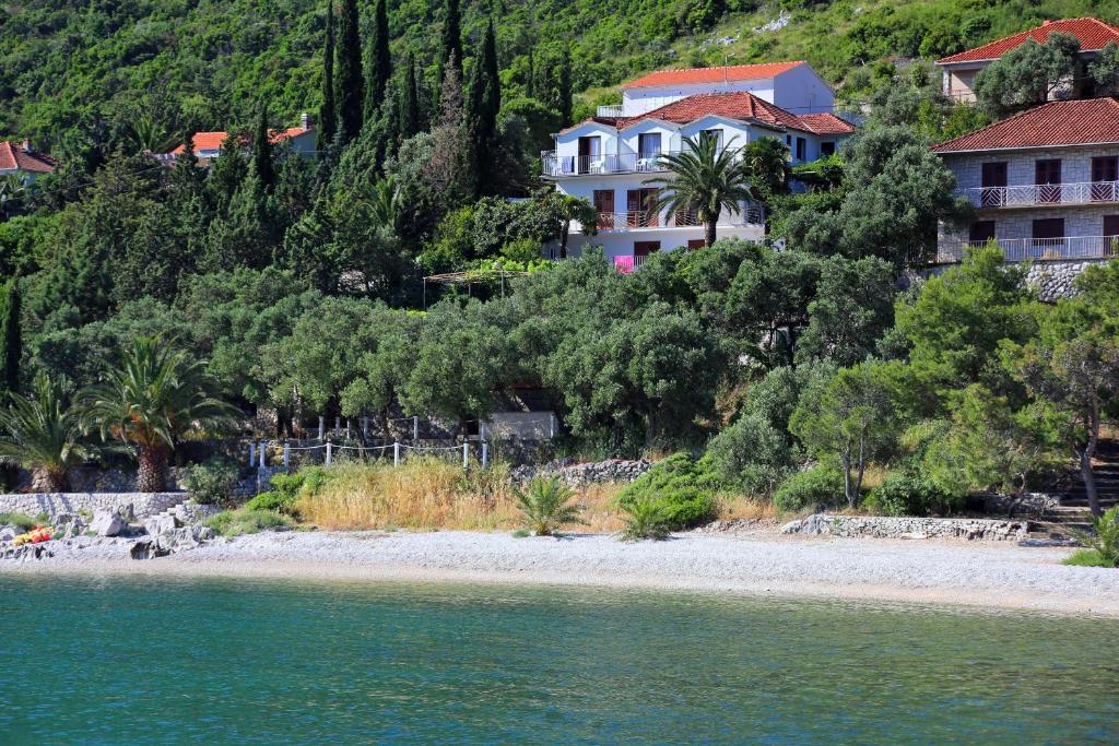 a house on a hill next to a body of water at Apartments and rooms by the sea Trpanj, Peljesac - 258 in Trpanj