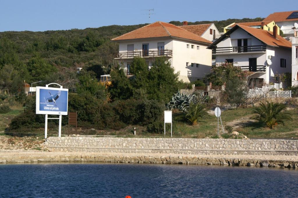 um sinal em frente a uma casa ao lado de uma massa de água em Apartments by the sea Sveti Petar, Biograd - 358 em Sveti Petar