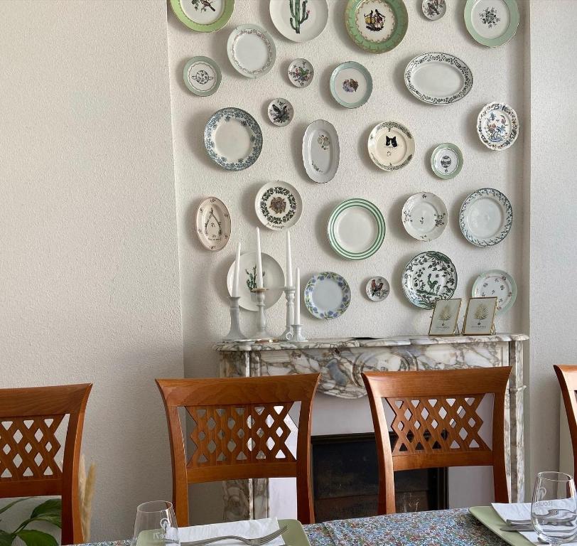 a dining room with plates on a wall at La Rose des vents in Saint-Symphorien-de-Marmagne