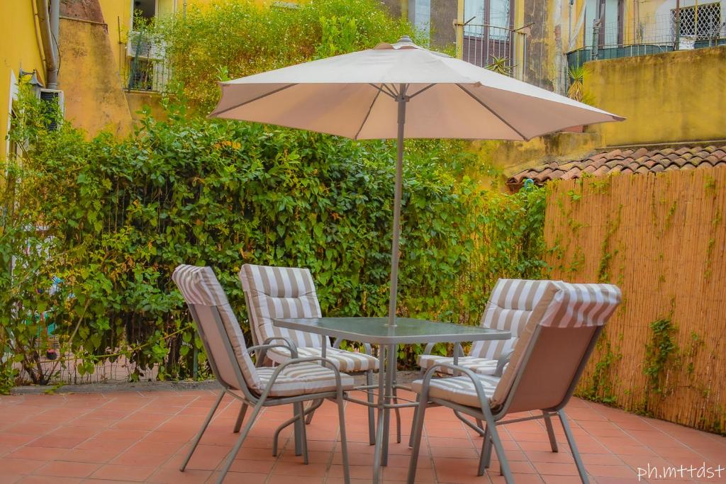 uma mesa com cadeiras e um guarda-sol num pátio em Palazzo Mannino Apartments em Catânia