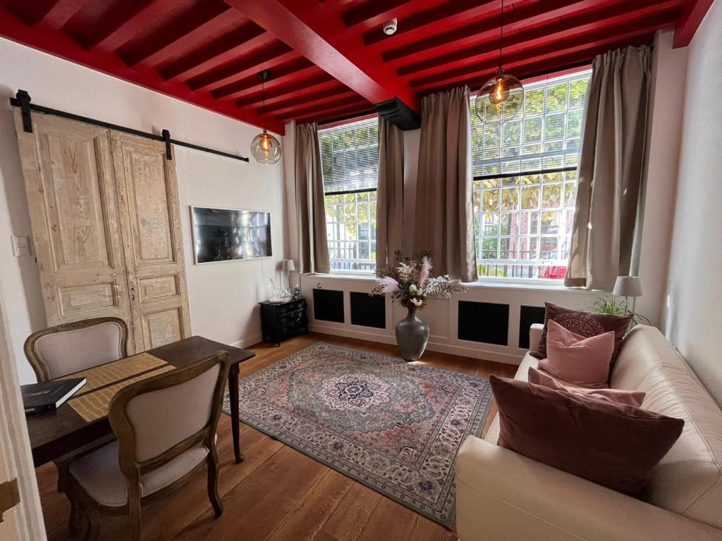 a living room with a couch and a table and two windows at Het Waterhof in Leiden