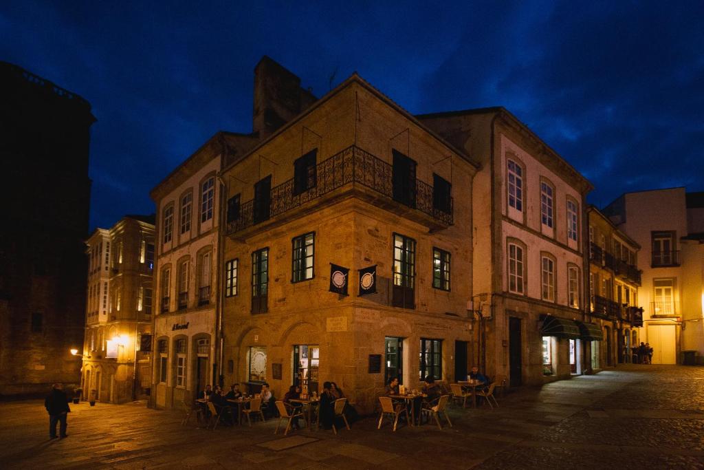 an old building with people sitting outside of it at night at Hospederia Tarela in Santiago de Compostela