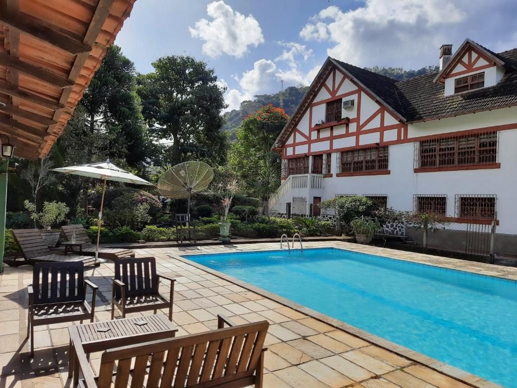 uma piscina com duas cadeiras e uma casa em Agellum Bed & Breakfast em Domingos Martins