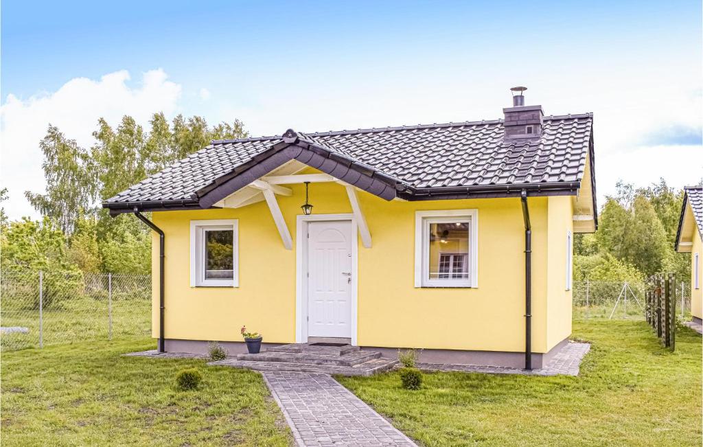 a yellow tiny house with a white door at Beautiful Home In Dabki With 2 Bedrooms, Wifi And Outdoor Swimming Pool in Dąbki