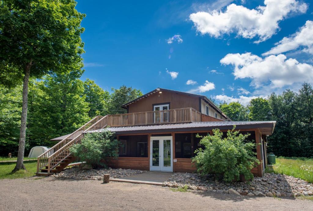 a log home with a porch and a deck at Algonquin Madawaska Lodge Cottage Glamping Cabins in Madawaska