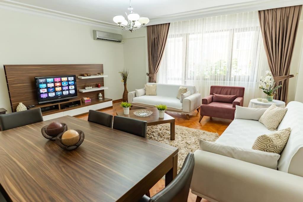 a living room with a table and chairs and a tv at Kaplan Cosy Flat - All air conditioned & Heated 3 Bedrooms in the City in Istanbul