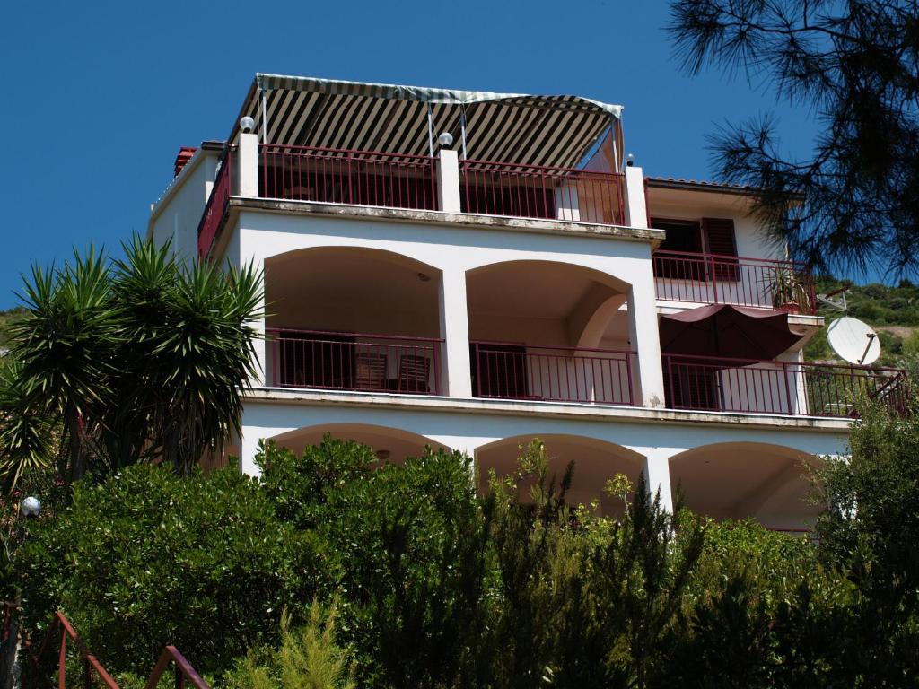 - un bâtiment blanc avec un balcon et des palmiers dans l'établissement Apartments by the sea Brna - Vinacac, Korcula - 13344, à Prižba