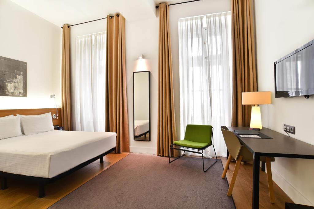 a hotel room with a bed, chair, desk and television at Hotel Zenit Budapest Palace in Budapest
