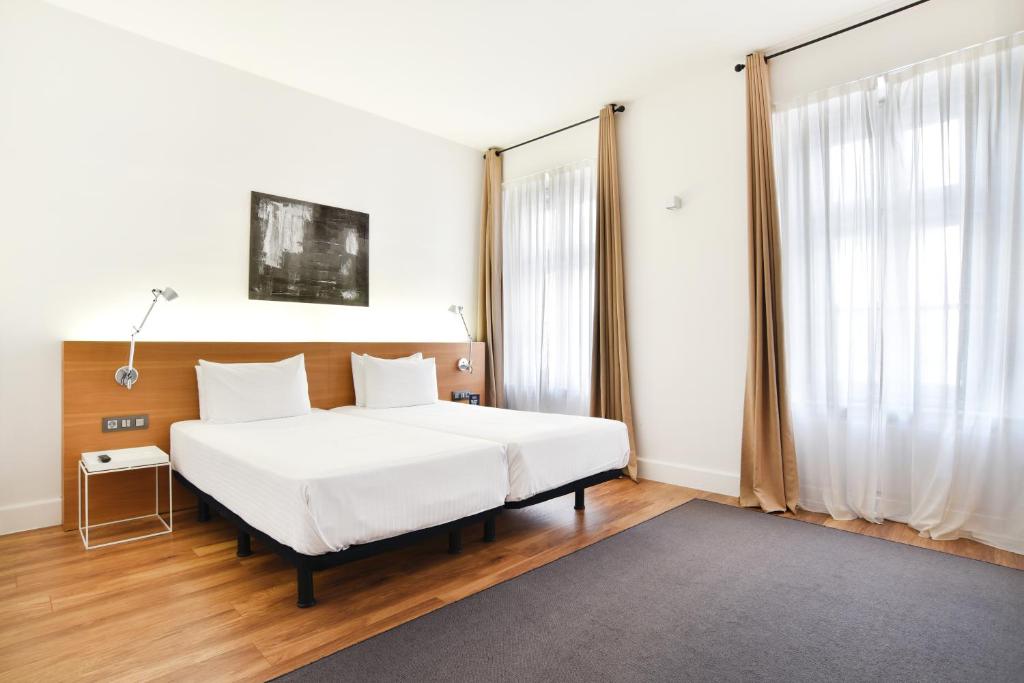 a bedroom with a white bed and a large window at Hotel Zenit Budapest Palace in Budapest