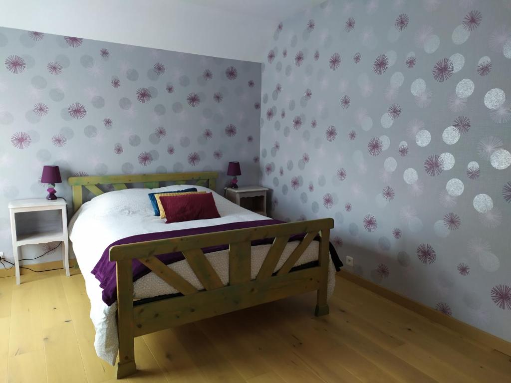 1 dormitorio con cama de madera y flores rosas en la pared en Entre mer et bocage, en Coutances