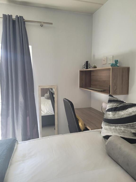 1 dormitorio con cama blanca y espejo en Ollies en Pretoria