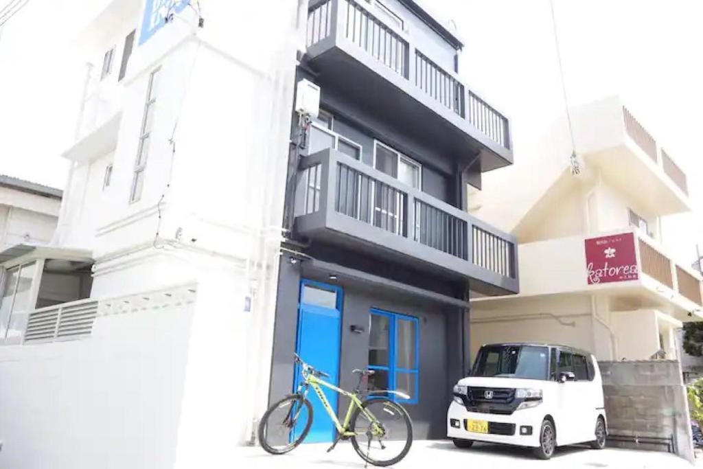 a bike parked next to a building with a car at 大家族向け貸切宿 敷地内無料駐車場 最高のロケーション 各階独立鍵付き個室 Paradise inn牧志 in Naha