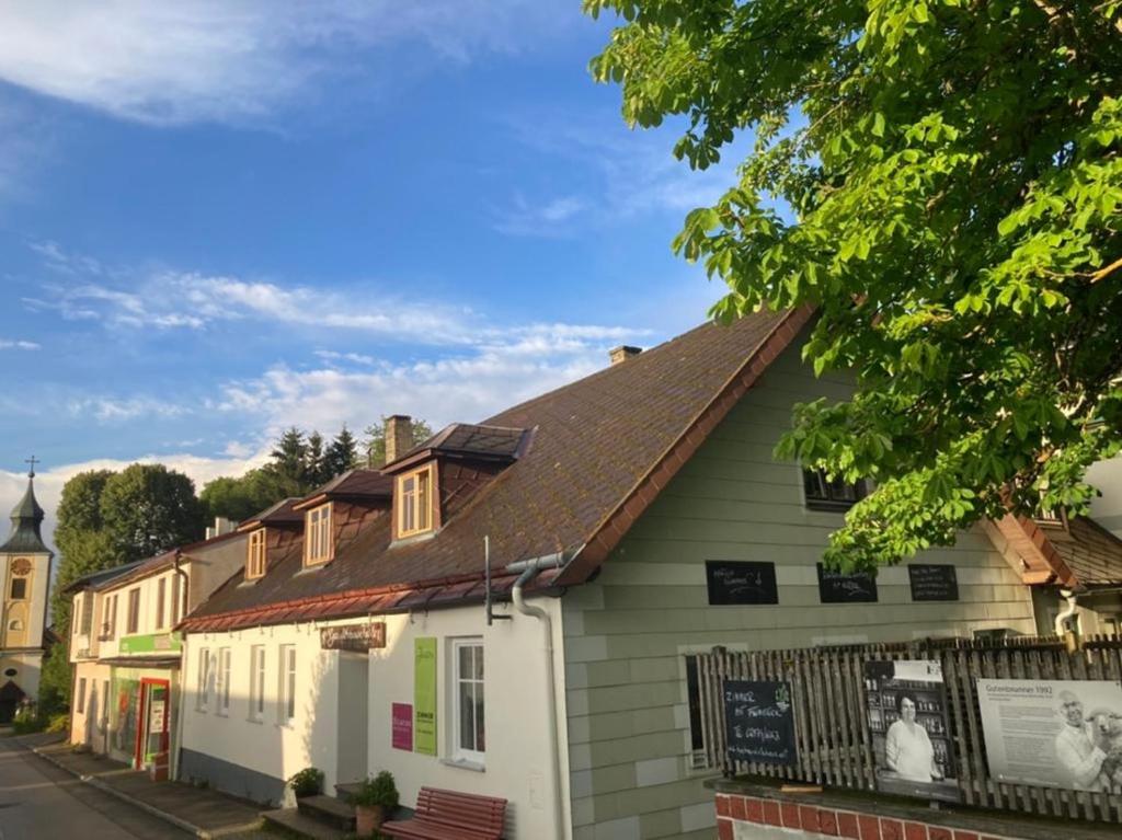 a white house with a brown roof on a street at Bühnenwirtshaus Juster in Gutenbrunn