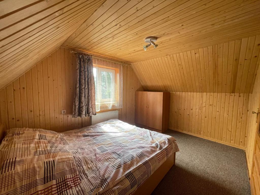 - une chambre avec un lit dans une cabane en bois dans l'établissement Mini Cottage, à Yablunytsya