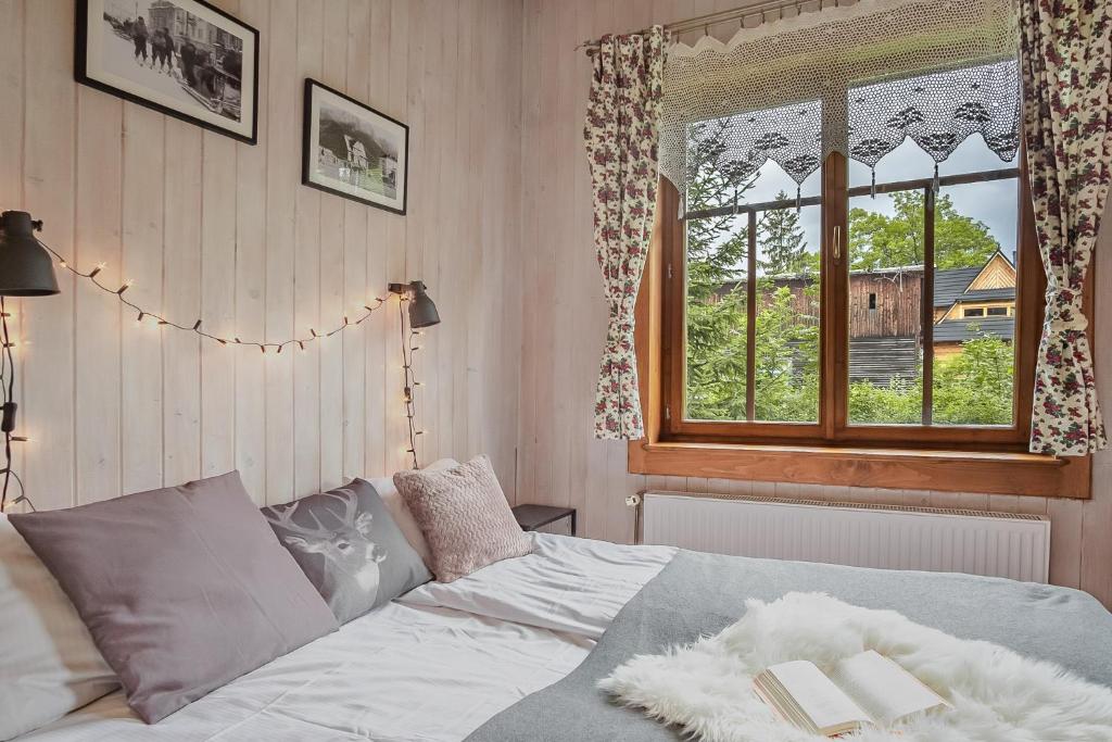 a bedroom with a bed with a window and books on it at Pokoje Samo Centrum in Zakopane