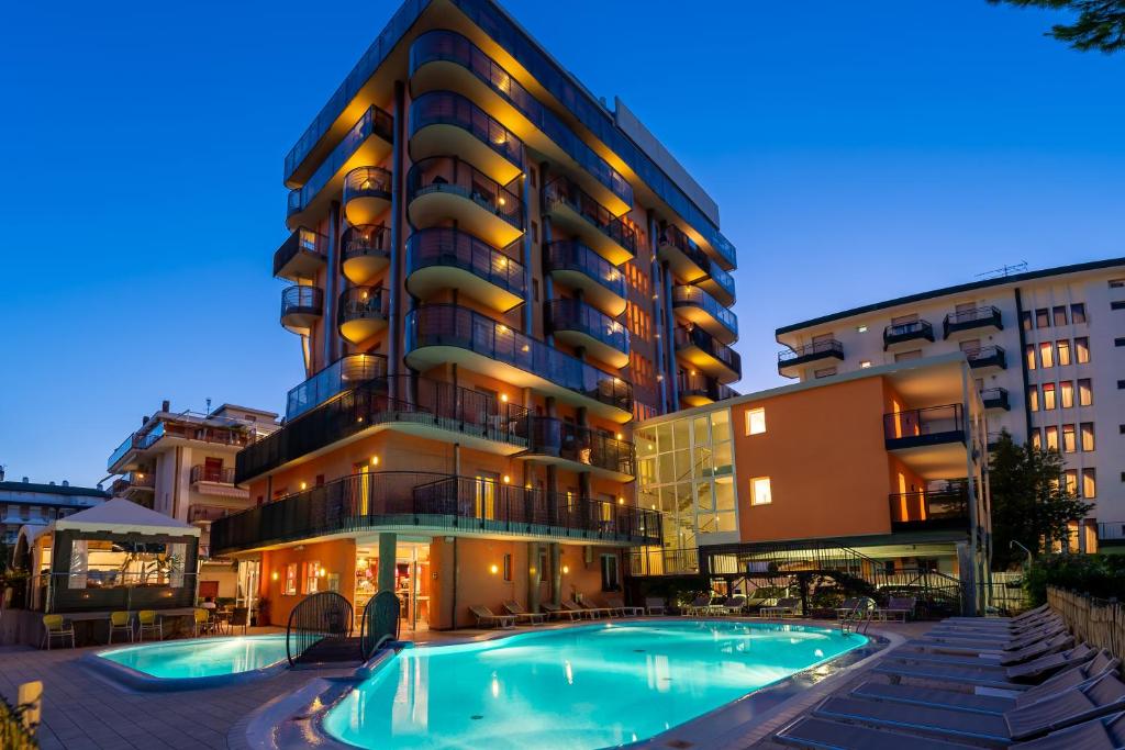 a hotel with a swimming pool in front of a building at Hotel Sheila in Lido di Jesolo