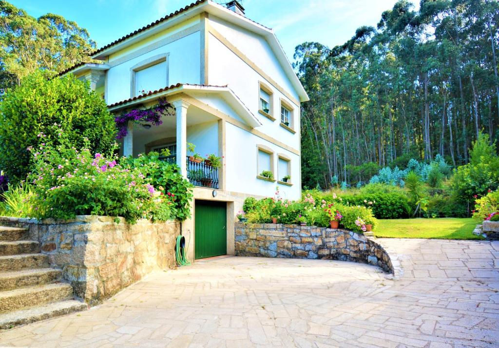 a house with a green door and a stone wall at GALIHOST - Finca de Roque in O Grove
