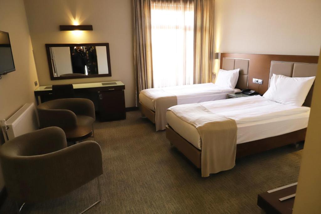 a hotel room with two beds and a chair at HİTİT OTEL in Ankara