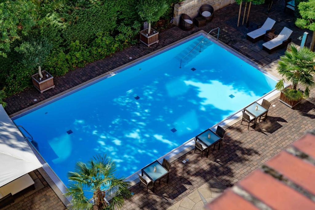 - une vue sur une grande piscine bleue avec des chaises dans l'établissement Mercure Hotel Hannover Medical Park, à Hanovre