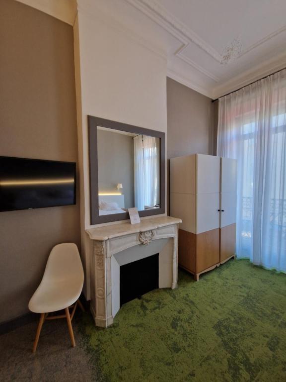 a room with a fireplace and a mirror and a refrigerator at Hôtel La Villa Tosca in Cannes