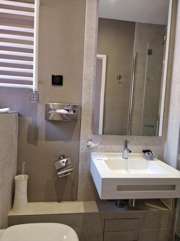 a bathroom with a sink and a mirror and a toilet at Hôtel La Villa Tosca in Cannes