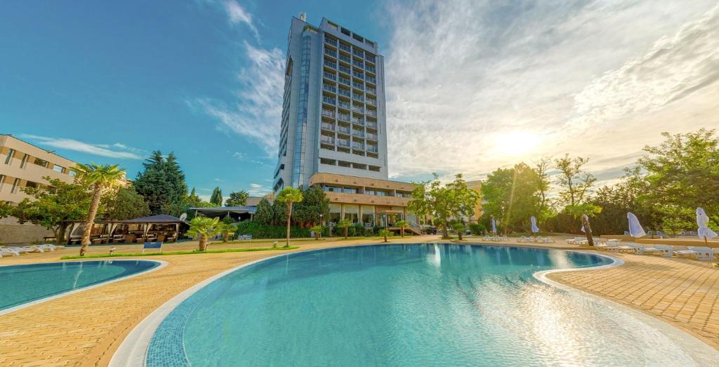 a large swimming pool with a tall building in the background at Kamenec Hotel in Nesebar