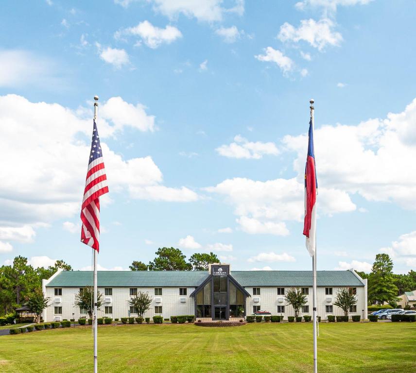 two flags in front of a white building at Carolina Pine Inn near Southern Pines-Pinehurst in Pinebluff