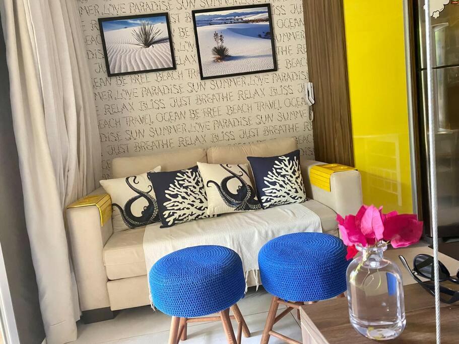 a living room with a couch and two blue stools at Flat Solar Água 127 - Family & Friends in Pipa