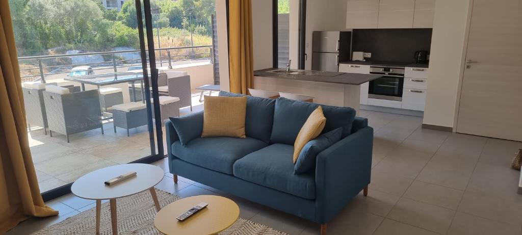 a living room with a blue couch and a kitchen at Appartement T3 proche du Port in Porto-Vecchio