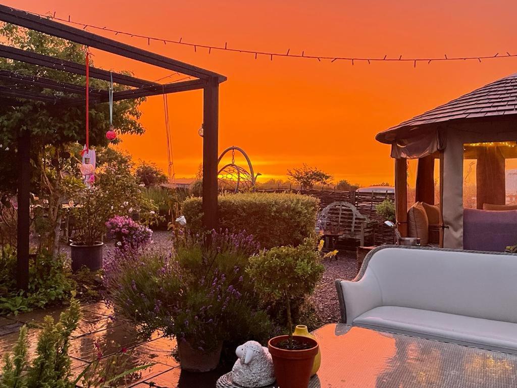 a sunset in a garden with a white couch at Bybrook Barn Bed & Breakfast in Loughborough