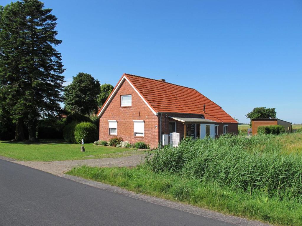 una casa de ladrillo rojo al lado de una carretera en Ferienhaus STICKLIESEL DITZ125, en Ditzum