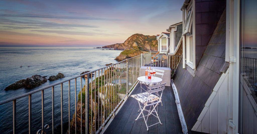 a balcony with a table and chairs on the ocean at No 5 Compass - Ilfracombe in Ilfracombe