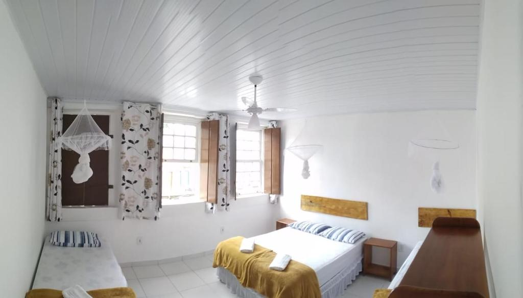 a white bedroom with two beds and a window at O Pouso Sobrado in Mucugê